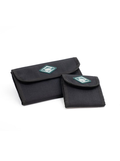 Two black cap pouches with flap closures and teal logo patches