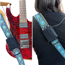 Black fabric pouch with snap flap, worn on a patterned guitar strap