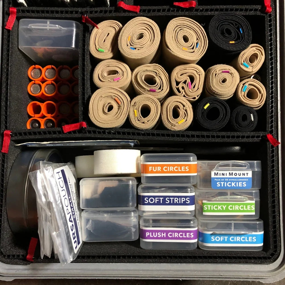 Organizer box with rolled beige and black strap pouches and small accessory rolls