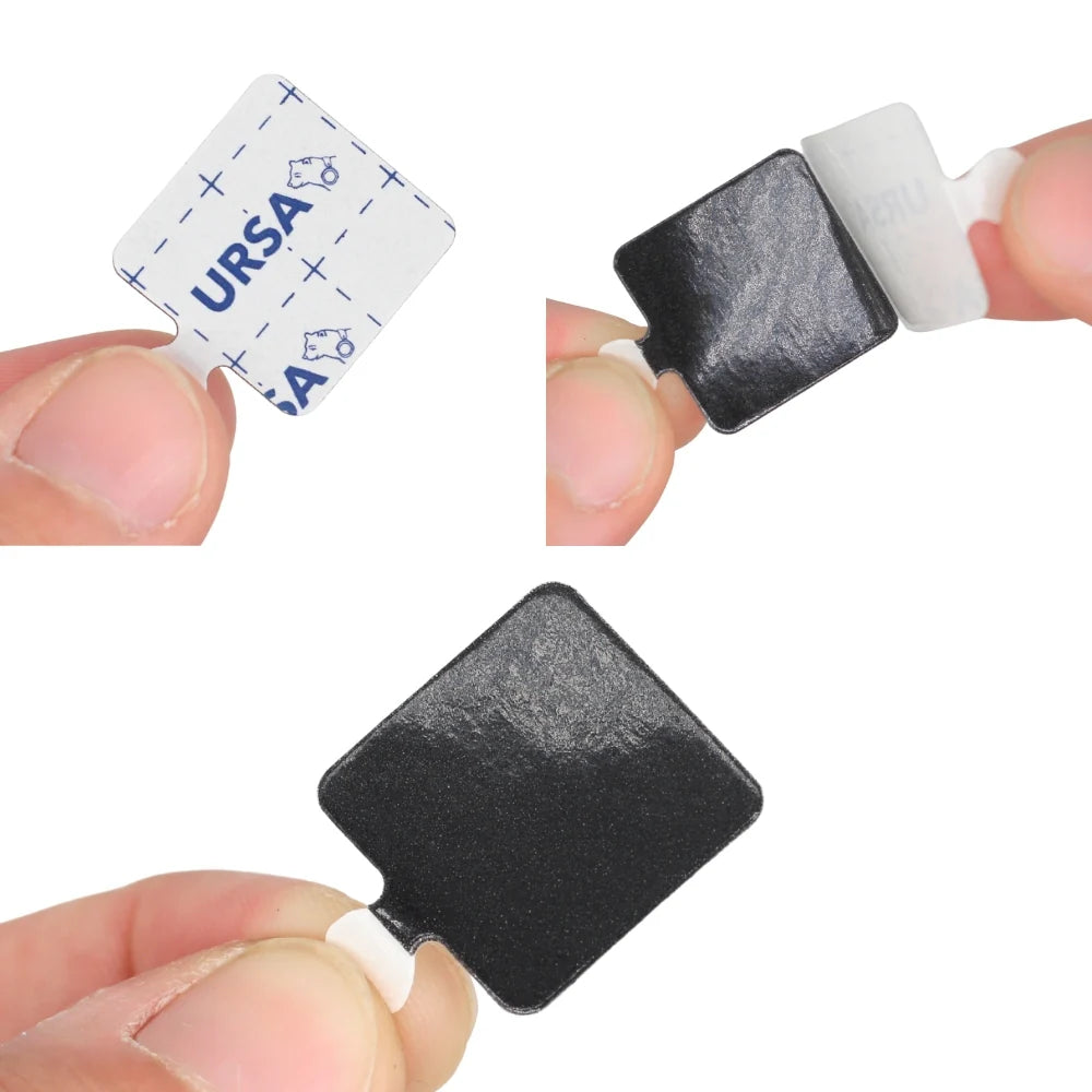 Hand holding a dark gray sticky square adhesive pad with peel backing