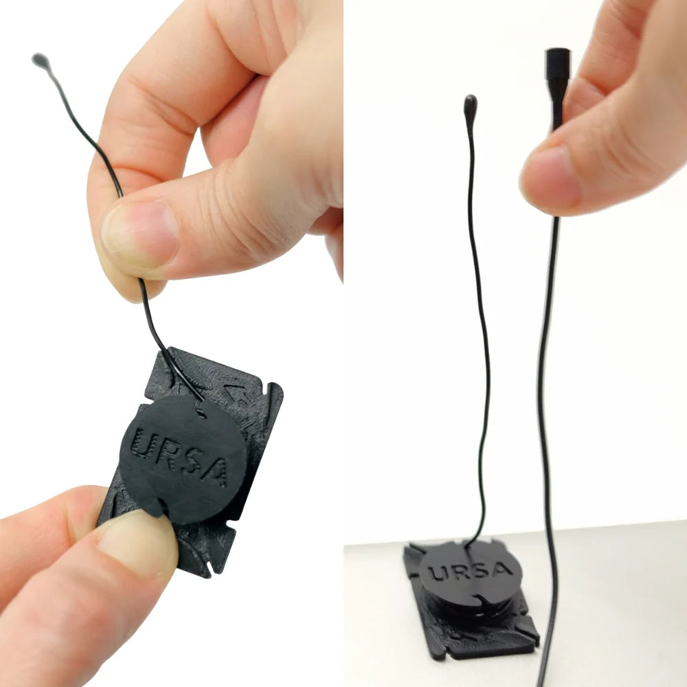 Hand holding a black URSA clip mic with cord attached for mounting