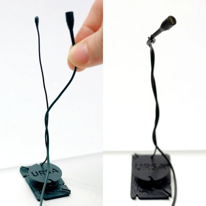 Two black URSA clip mics with thin cords, lifted and held by hands