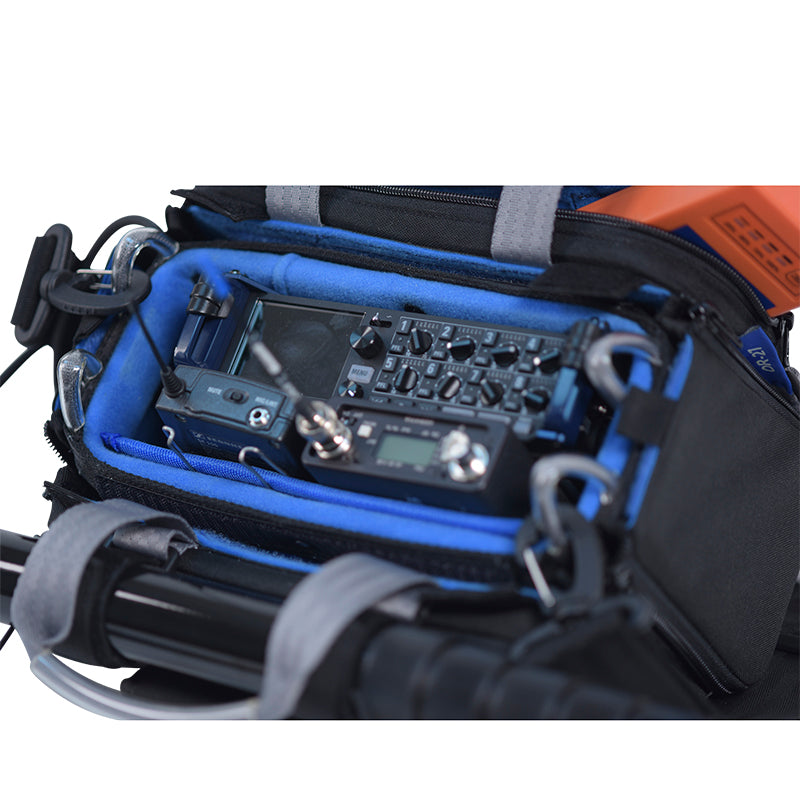 Small audio mixer case bag close-up with blue lining, mixer controls, and coiled cables.