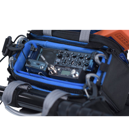 Small audio mixer case bag close-up with blue lining, mixer controls, and coiled cables.