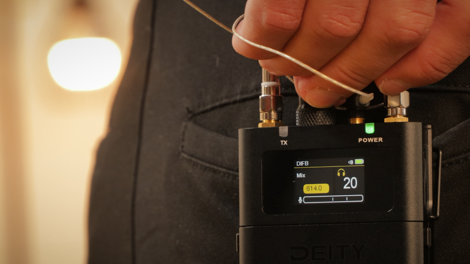 Black DEITY digital IFB receiver on a chest with LCD showing DBTX and power