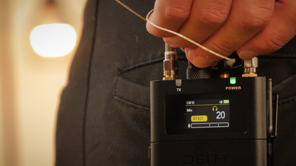Black DEITY digital IFB receiver on a chest with LCD showing DBTX and power
