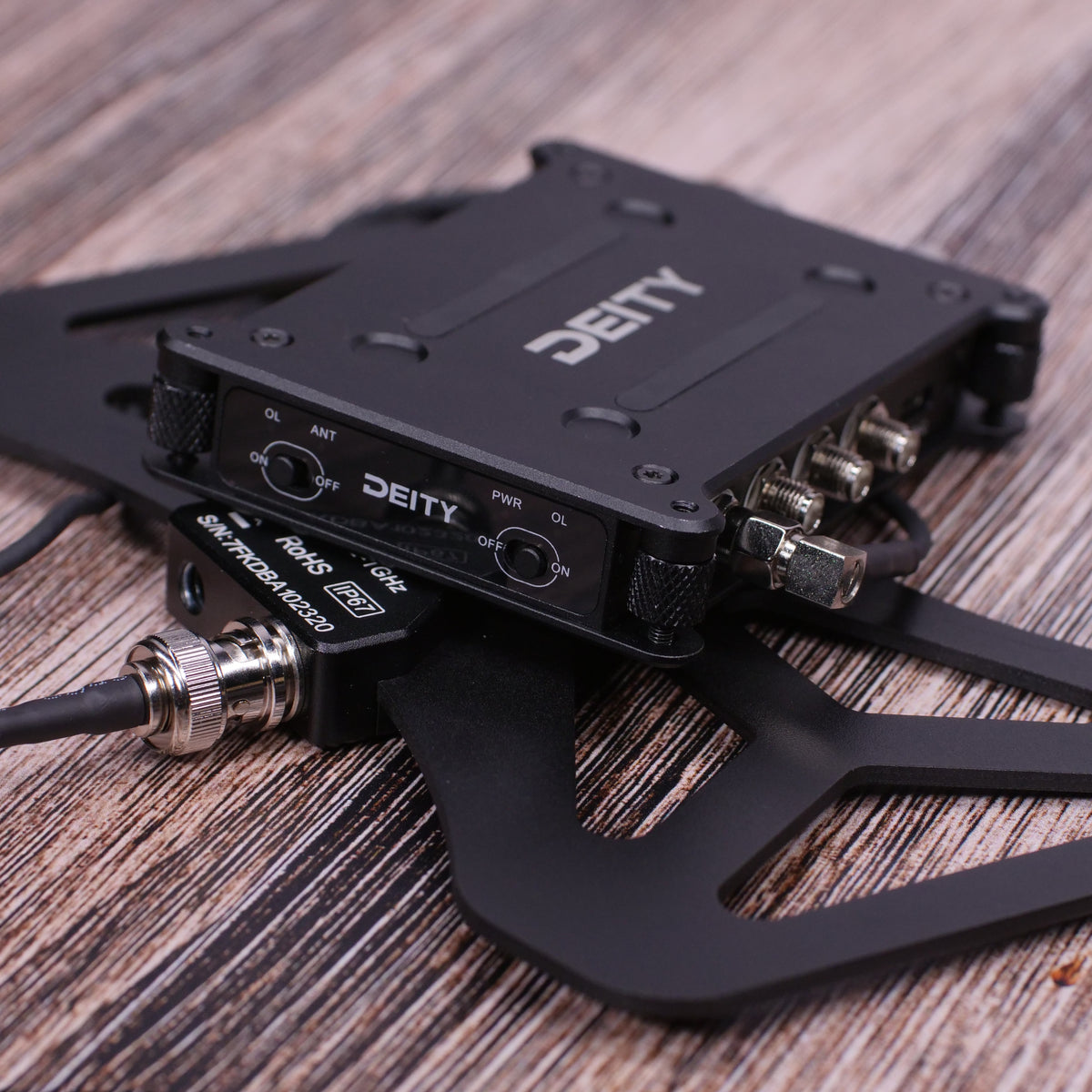 Black RF distributor unit with antenna and power ports on wood surface