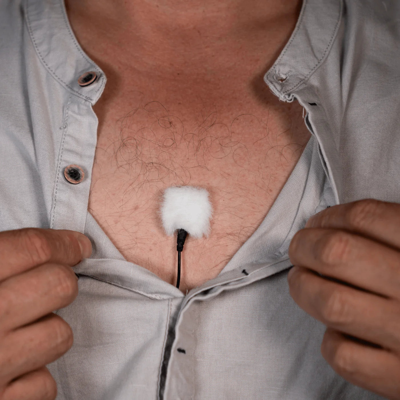 White lav mic cover pad placed on shirt front with cable