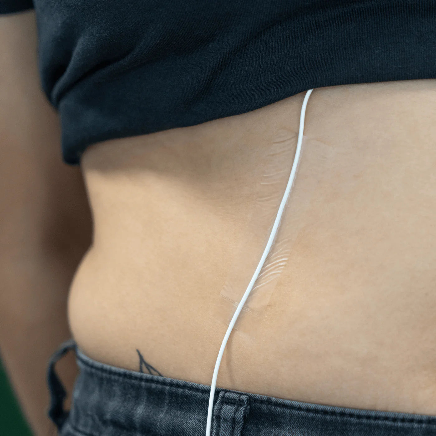 Invisible skin tape on skin beside waistband, thin clear strip