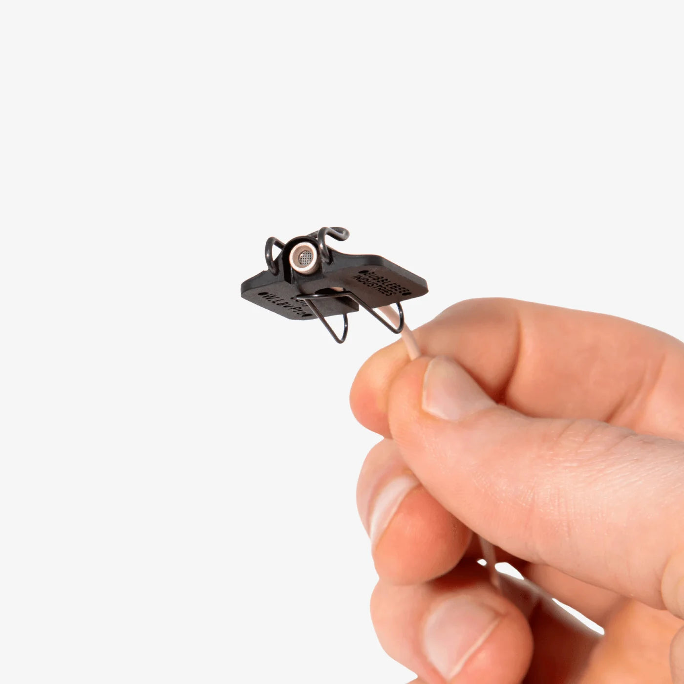 Black lav microphone concealer clip with small circular adjustment, held in a hand