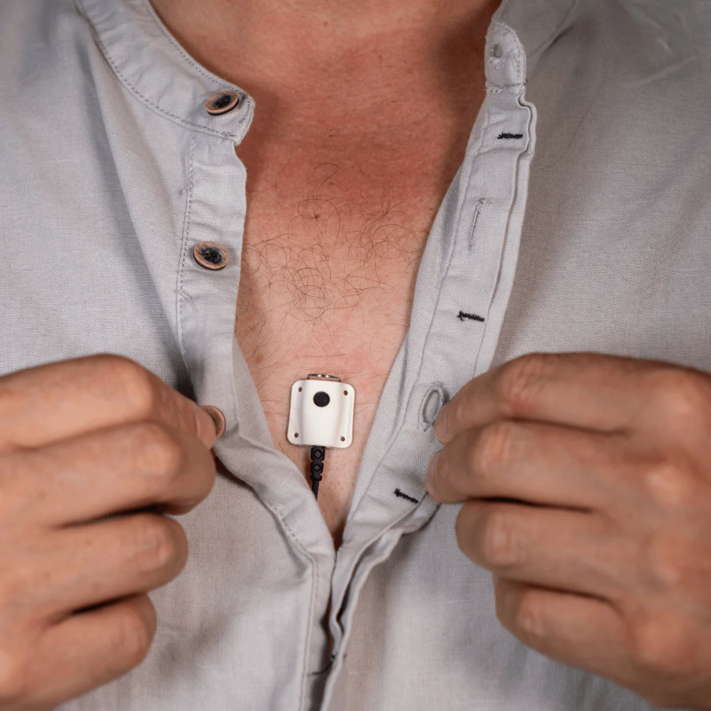 Lav mic concealer holding a microphone unit on a light button-up shirt