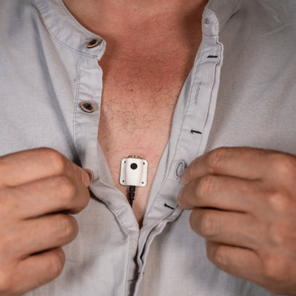 Lav mic concealer holding a microphone unit on a light button-up shirt