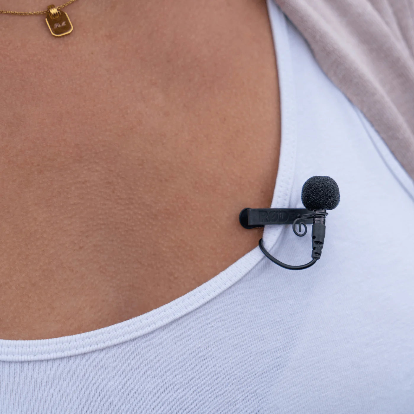 Black foam windscreen covering a clip-on lavalier microphone on a white shirt