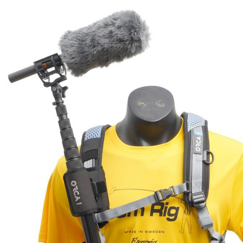 Magnetic boom pole holder: black clamp with strap and circular base, mounted on vest