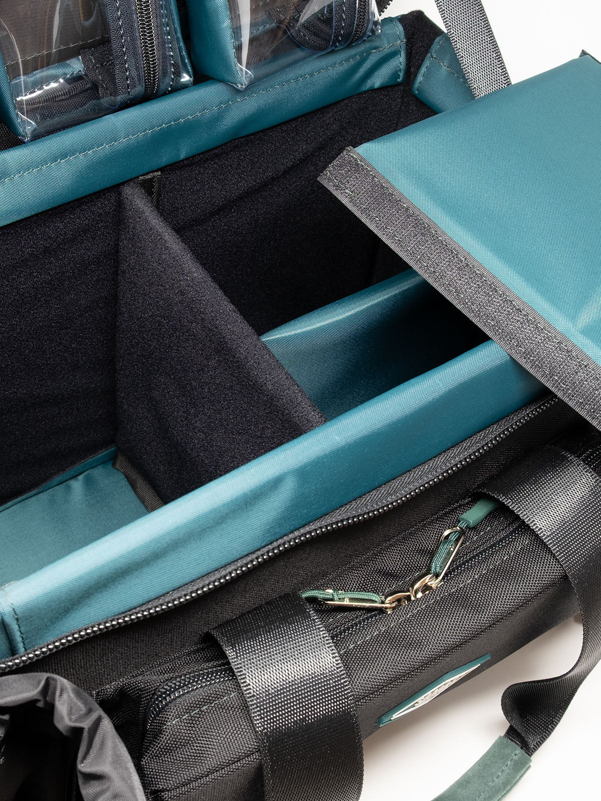 Accessory case interior with teal lining, divider pockets, and a zippered front pocket