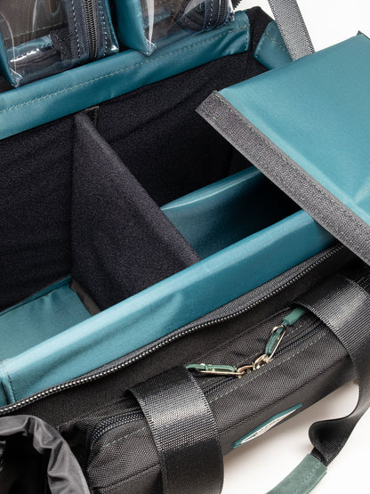 Accessory case interior with teal lining, divider pockets, and a zippered front pocket
