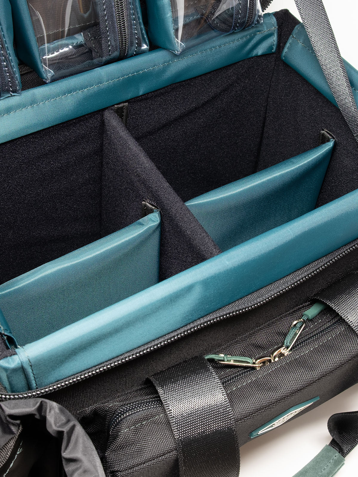 Accessory case interior view with teal dividers and a zippered pocket with clips