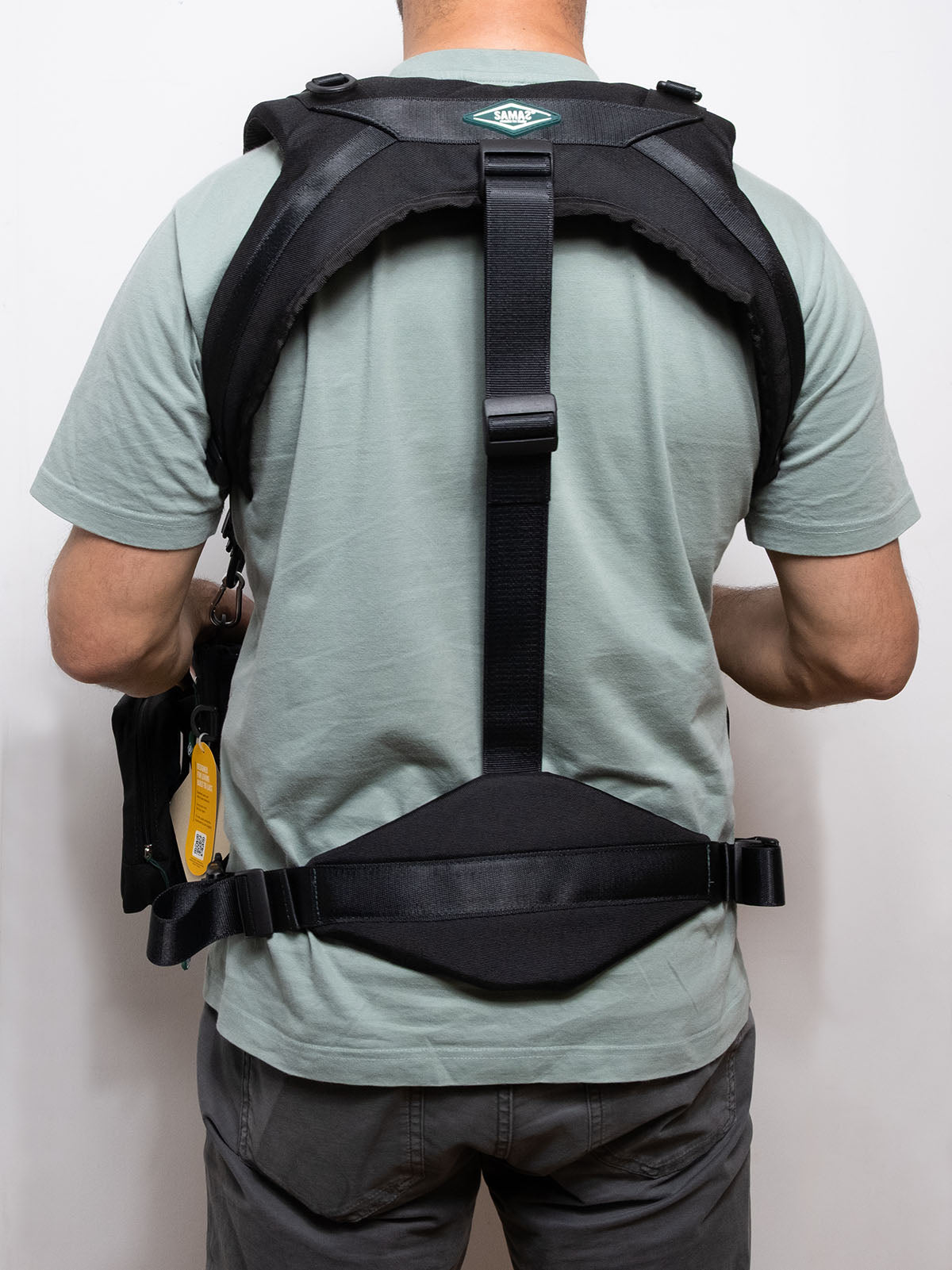 Black camera-style harness with vertical center strap and adjustable back support