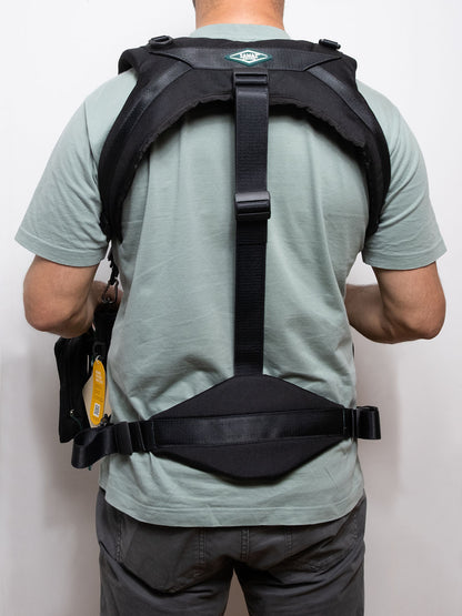 Black camera-style harness with vertical center strap and adjustable back support
