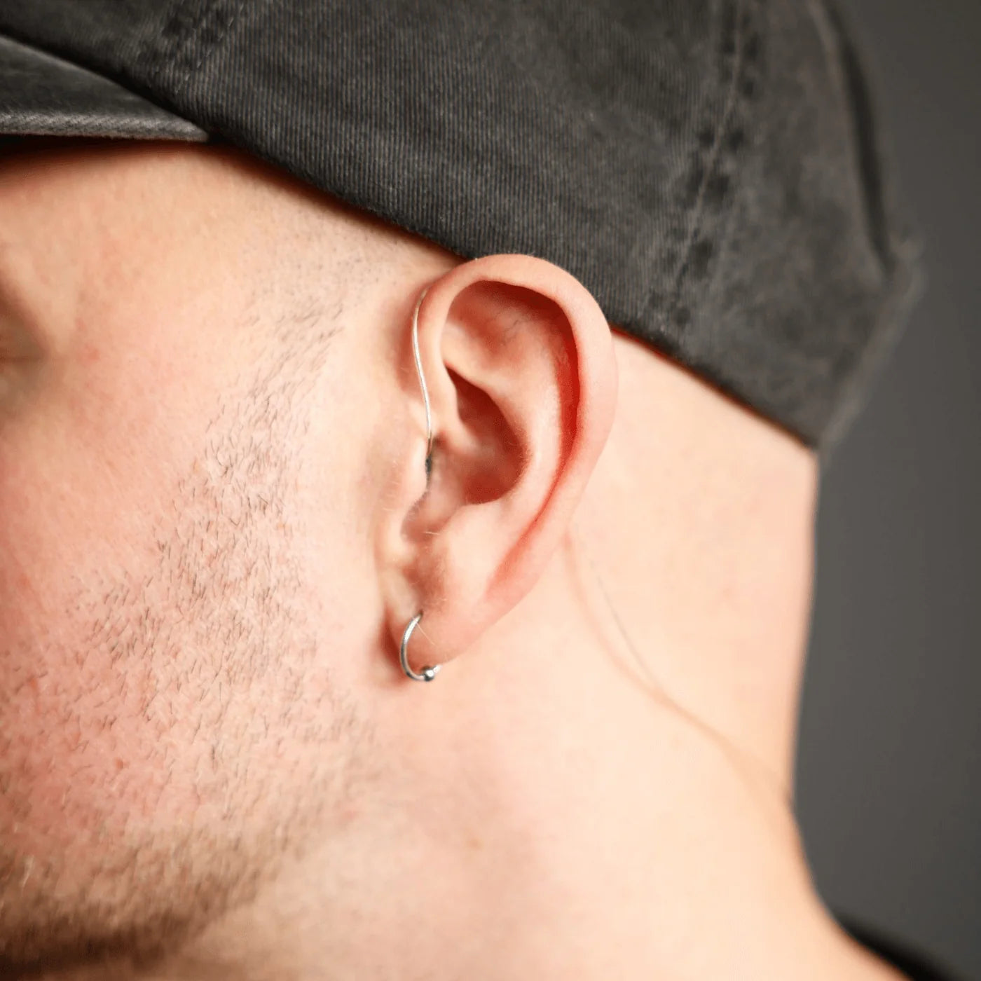 In-ear monitor fitted in ear with black earpiece and clear wire, close-up