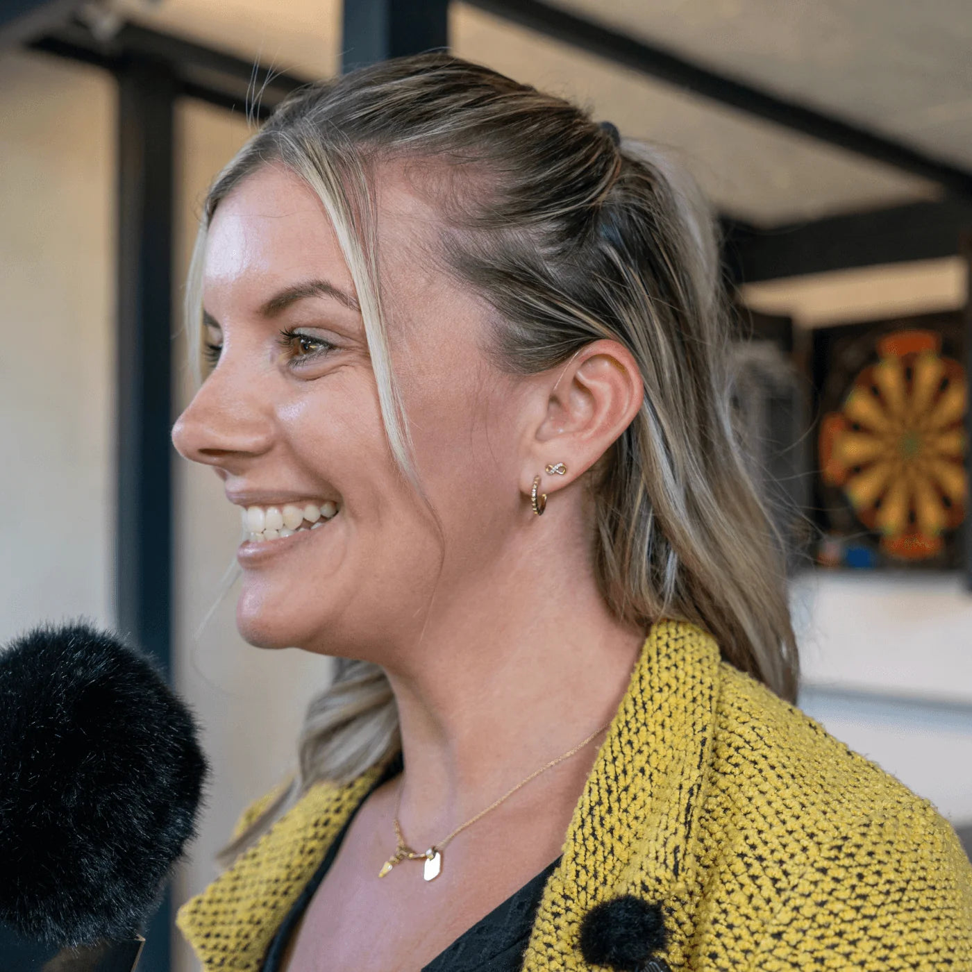Broadcast earpiece with ear-mounted mic and black cable, worn by a woman