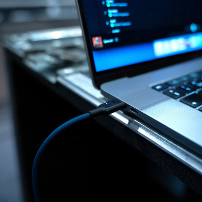 USB-C connector plugged into a laptop port with blue braided cable
