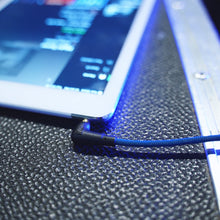 Audio cable connector plugged into a laptop, braided blue cord visible