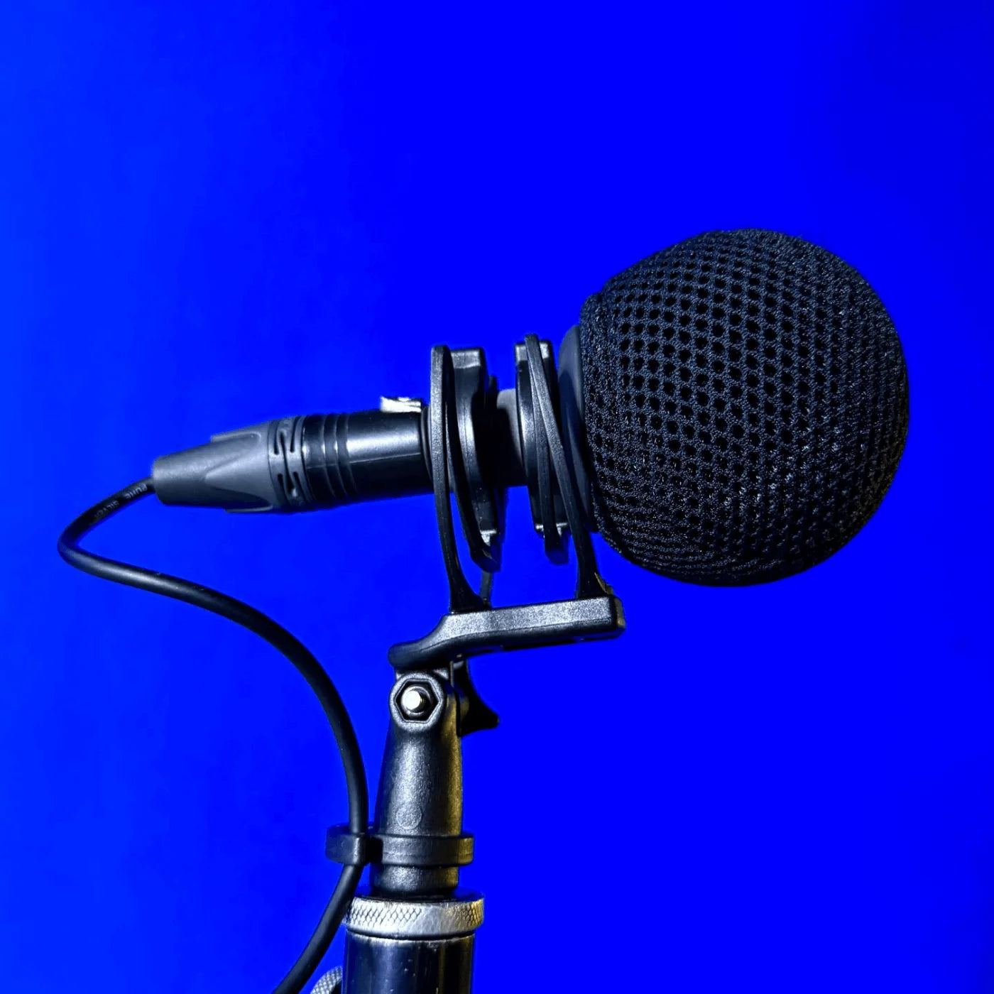 Black mesh microphone spacer ball attached to a studio mic on a stand