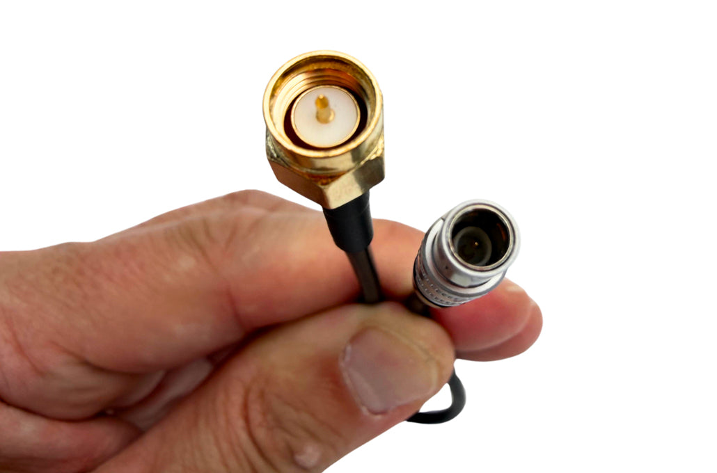 Hand holding black cable with gold connector and metal plug end
