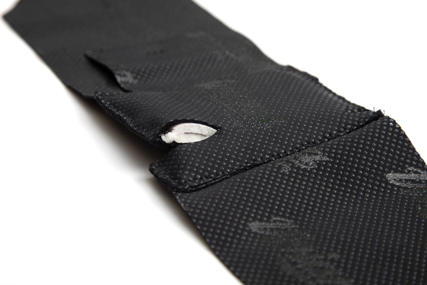 Black ankle strap with textured surface and Velcro loop tab detail