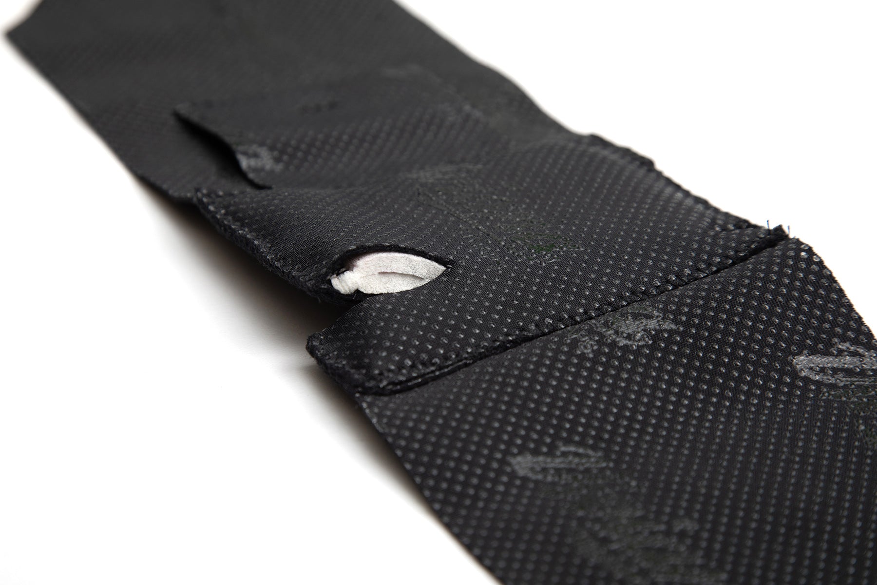 Black ankle strap with textured surface and Velcro loop tab detail
