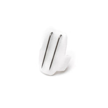 White beetle-shaped clip with two silver metal prongs, close-up