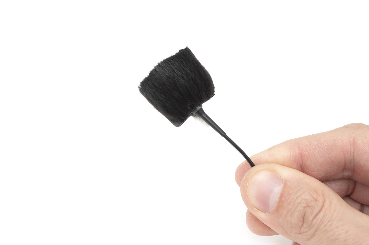 Hand holding sticker applicator with black foam brush tip on thin handle