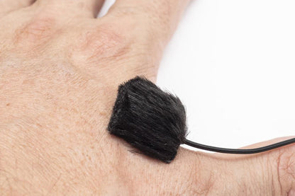 Black fuzzy pad attached near skin on a thin cable