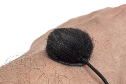 Black furry pad on a thin handle, shown against skin