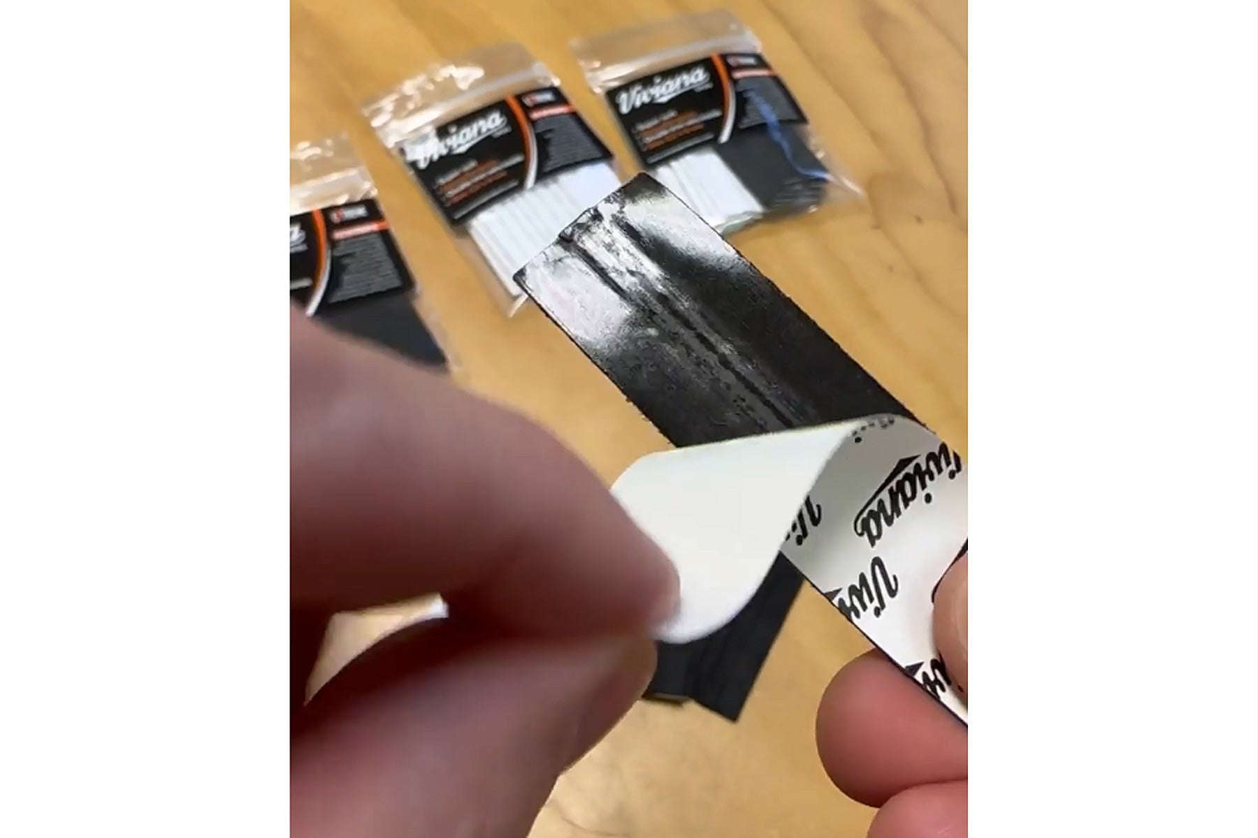 Self-adhesive moleskin strips held by hands on a surface