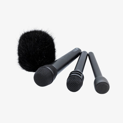 Three black fuzzy microphone windscreens on gray handheld mic bodies