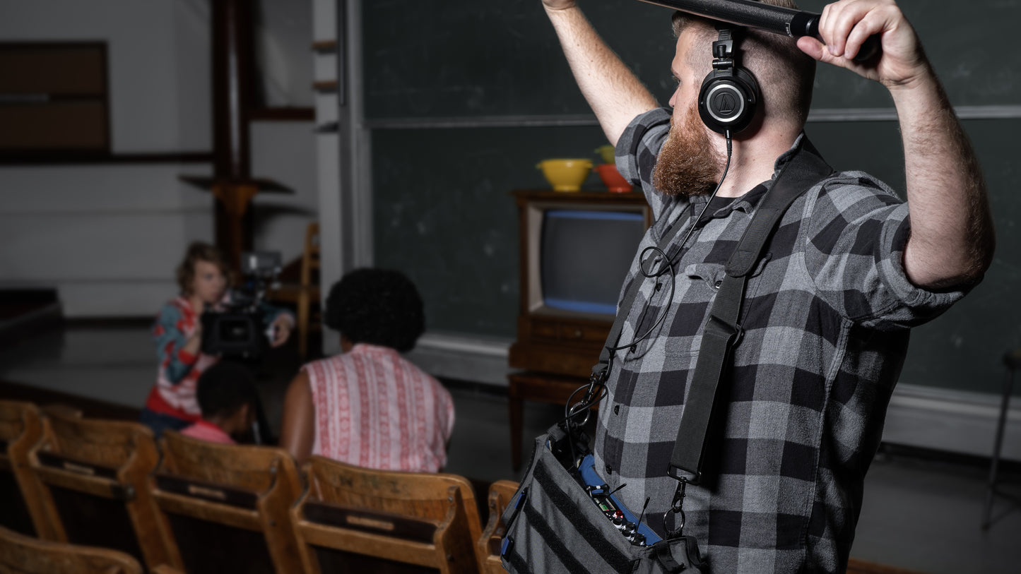 Person adjusting an audio mixer while wearing headphones and standing indoors
