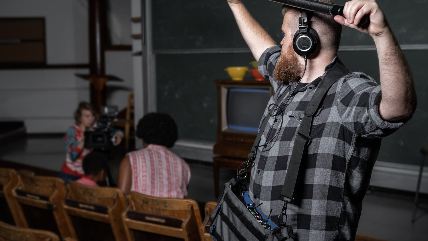 Person adjusting an audio mixer while wearing headphones and standing indoors