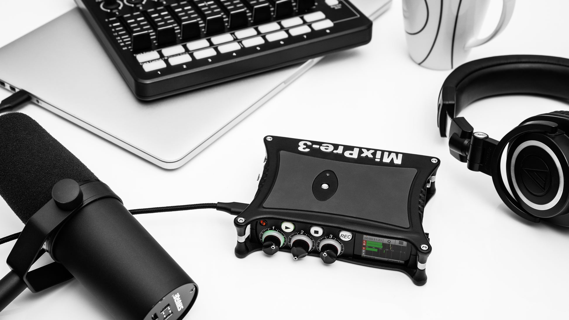 Portable audio recorder/interface on desk setup with cables, black unit with controls.