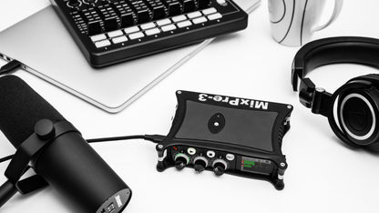Portable audio recorder/interface on desk setup with cables, black unit with controls.