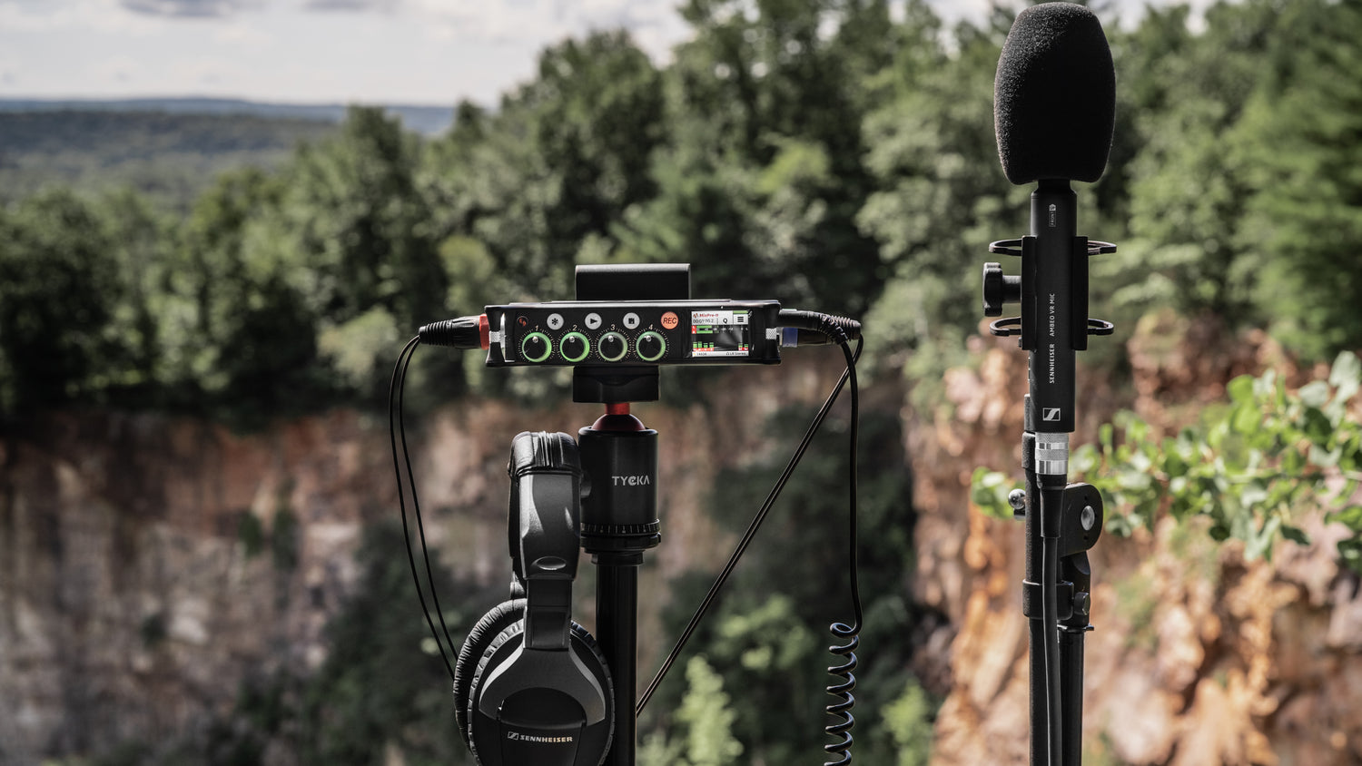 Audio mixer/preamp mounted on a stand with microphone and attached cables outdoors