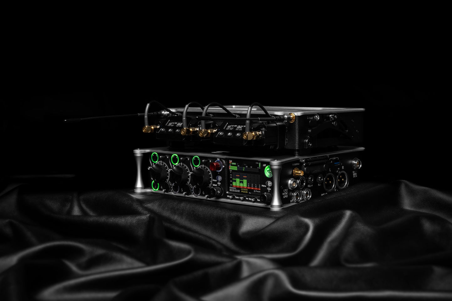 Black audio device on stand with front controls, display, and gold connector cables