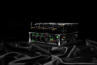 Black audio device on stand with front controls, display, and gold connector cables