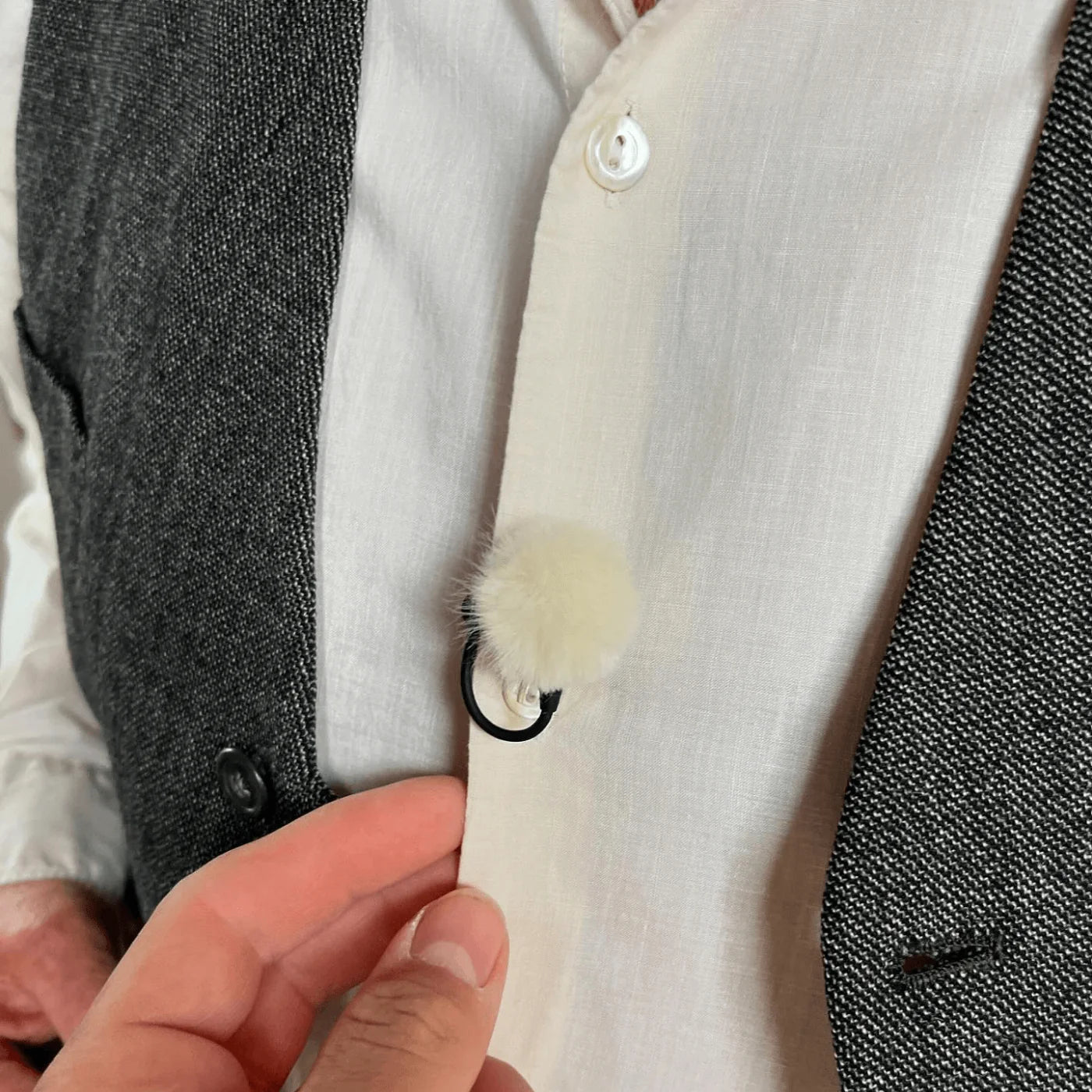 Light jacket with fuzzy windscreen pom-pom on a black cord clip
