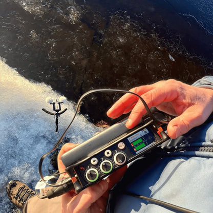 Furry windscreen microphone cover on a handheld audio recorder with cables