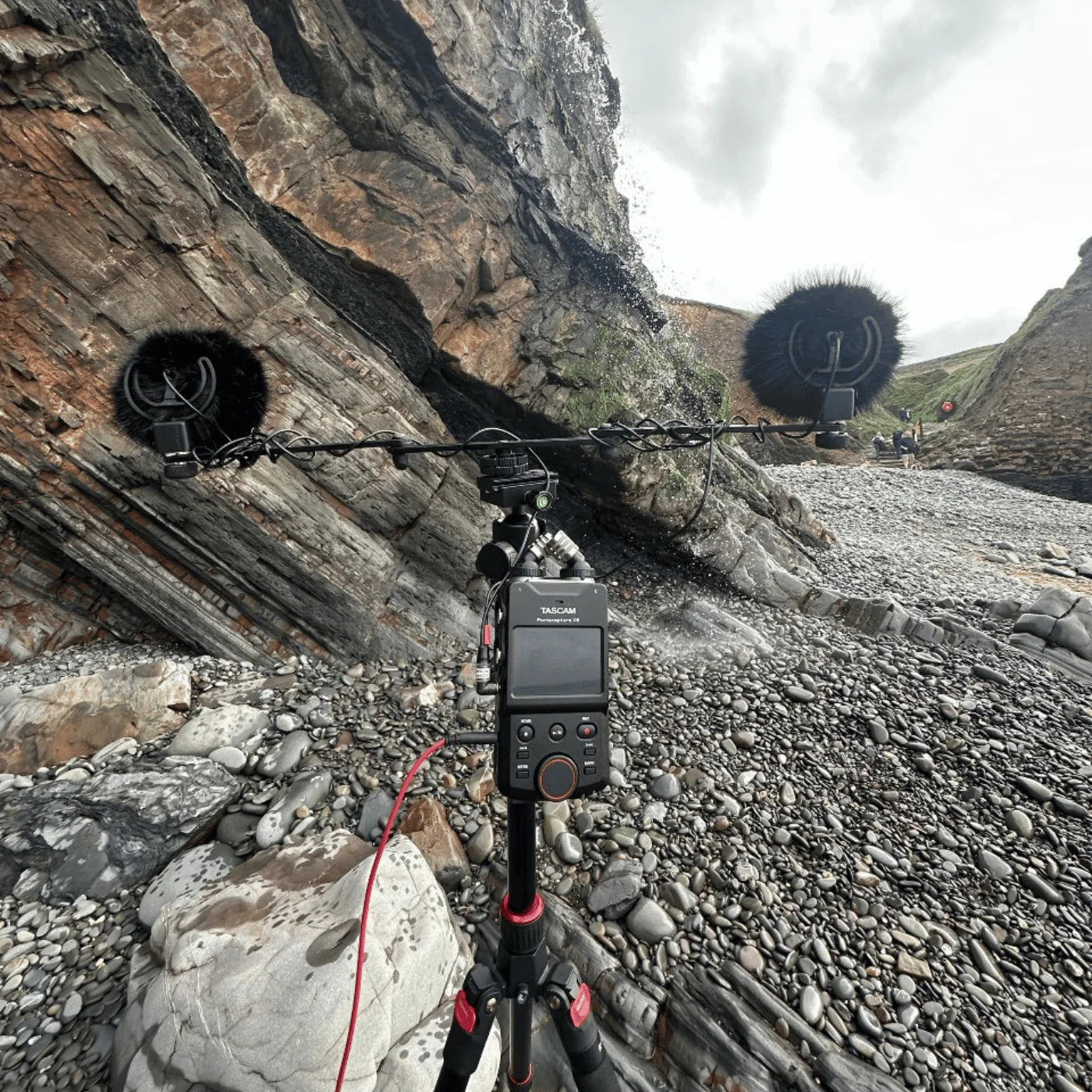 Black furry microphone windscreen cover on a field audio setup outdoors