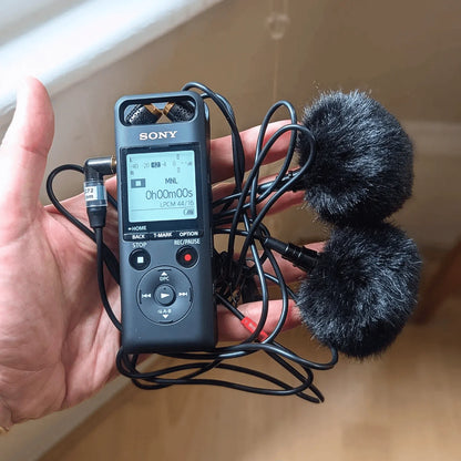 Black furry microphone windscreen cover attached to a portable recorder and cable