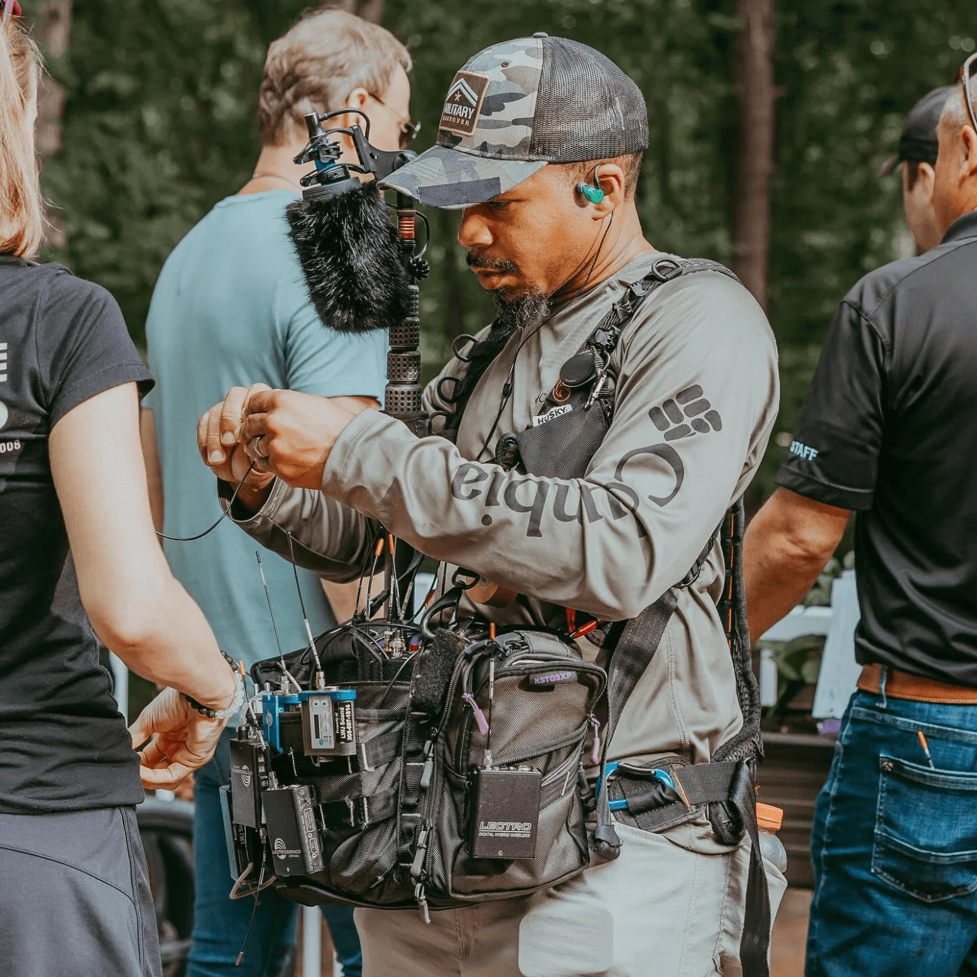 Furry black shotgun microphone windscreen on production boom mic setup outdoors