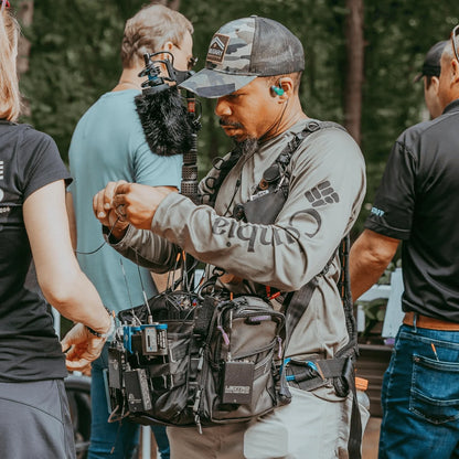 Furry black shotgun microphone windscreen on production boom mic setup outdoors